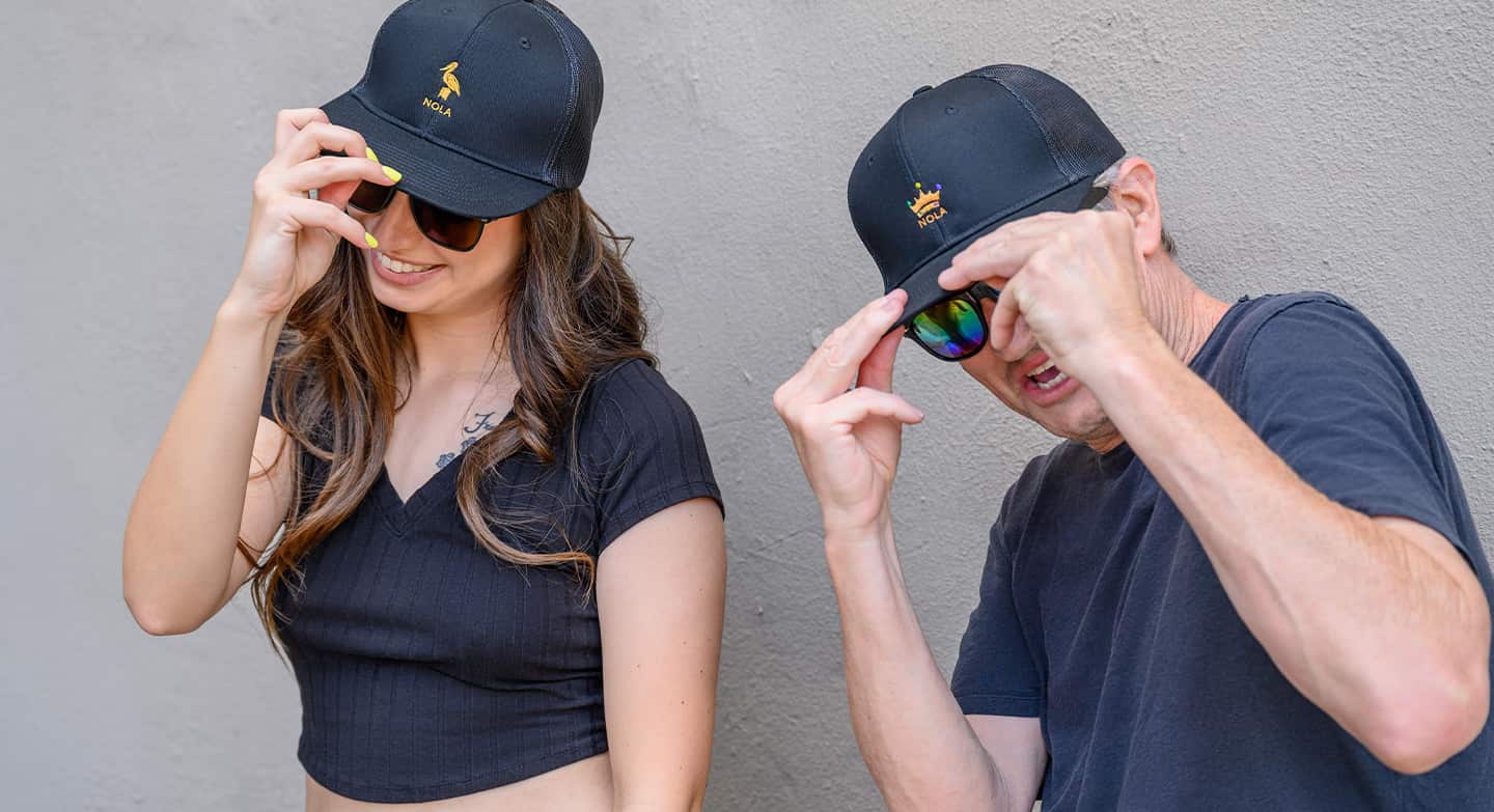 Man and woman touching their hats.